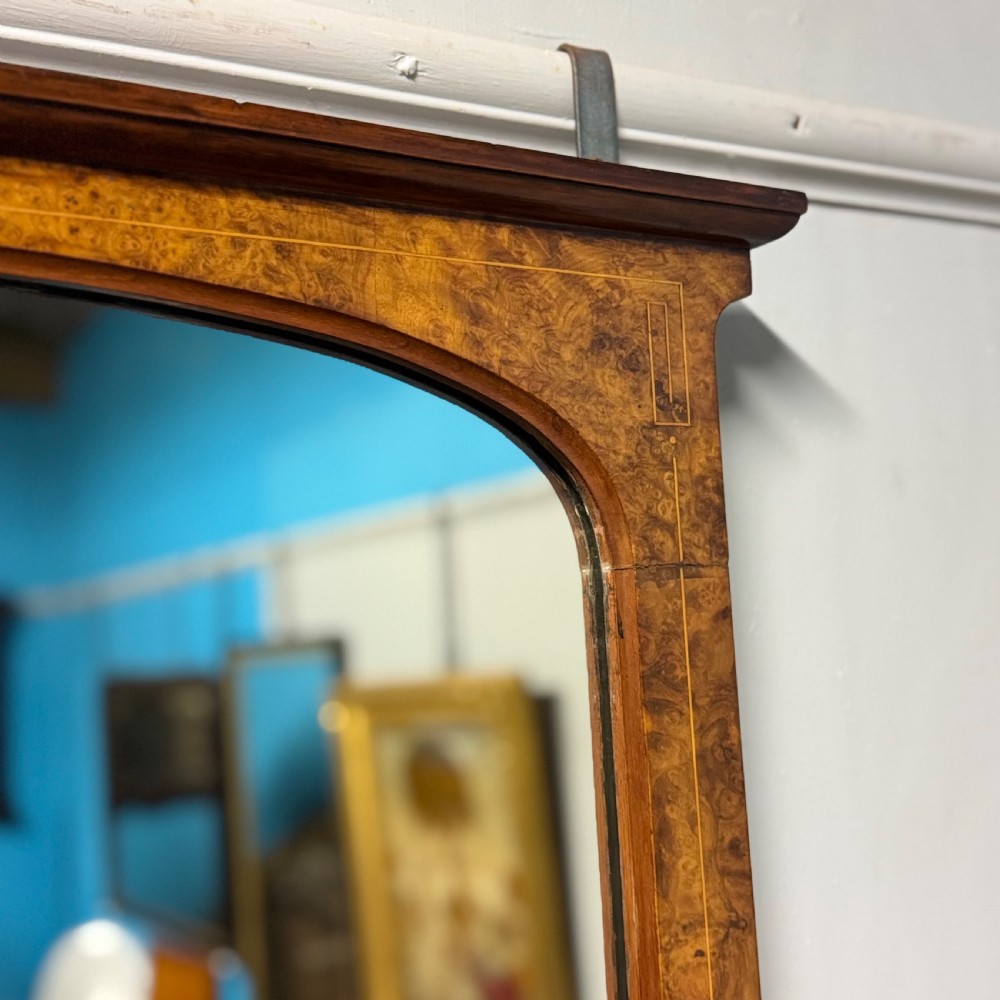 A wide antique burr walnut overmantel mirror featuring an arched upper frame, subtle stringing inlay, and stepped corner brackets. View II