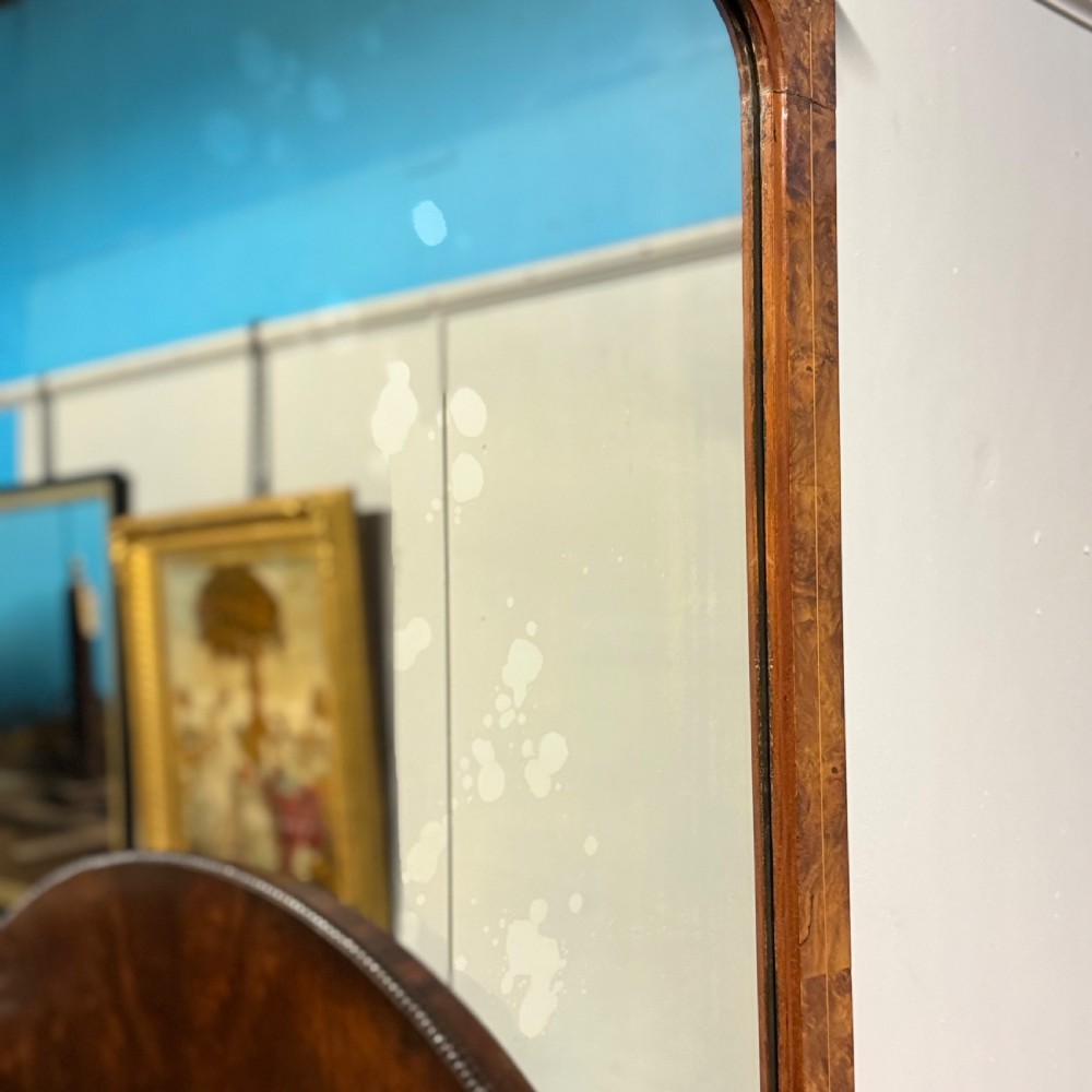 A wide antique burr walnut overmantel mirror featuring an arched upper frame, subtle stringing inlay, and stepped corner brackets. View III