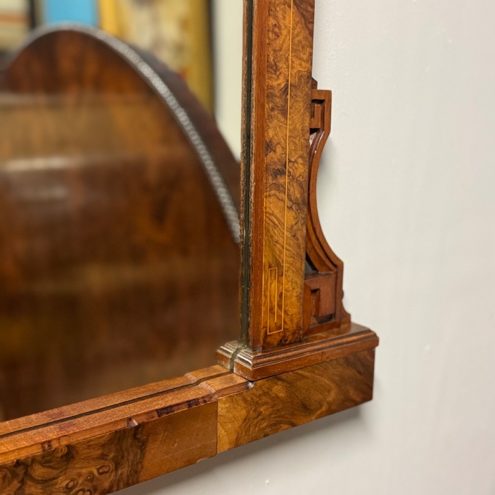A wide antique burr walnut overmantel mirror featuring an arched upper frame, subtle stringing inlay, and stepped corner brackets. View IV