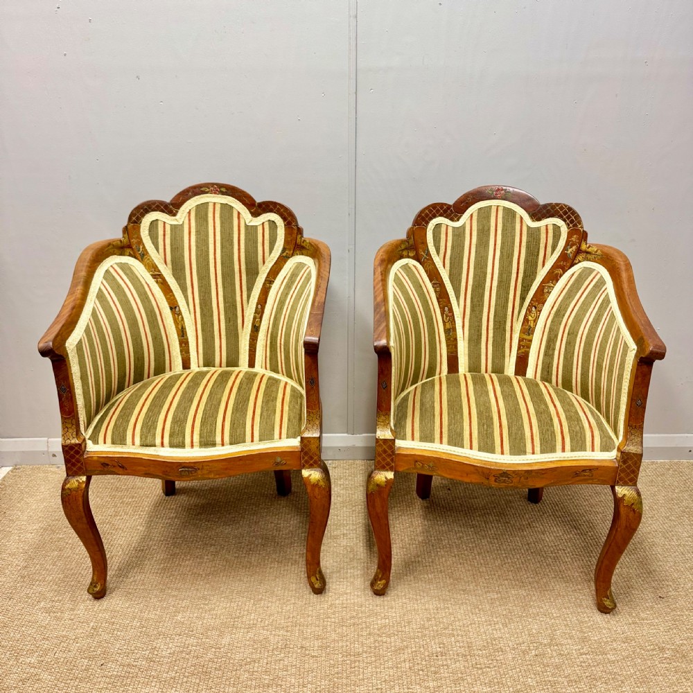 A pair of satinwood armchairs featuring hand-painted Chinoiserie detail, cabriole legs, and striped green, beige, and red fabric upholstery.