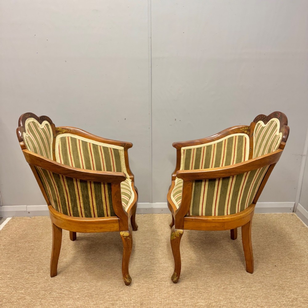 A pair of satinwood armchairs featuring hand-painted Chinoiserie detail, cabriole legs, and striped green, beige, and red fabric upholstery. View X