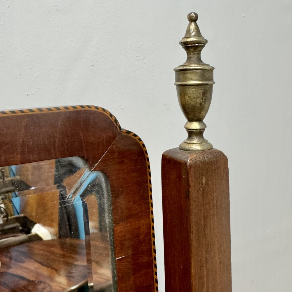 A Regency mahogany cheval mirror featuring a rectangular swivelling mirror frame, turned finials, boxwood inlay, and splayed legs ending in brass castors. View IV