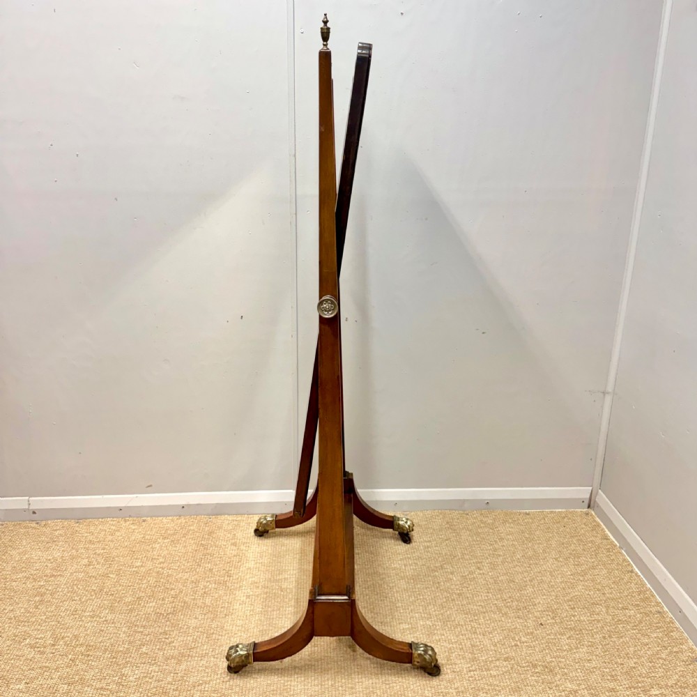 A Regency mahogany cheval mirror featuring a rectangular swivelling mirror frame, turned finials, boxwood inlay, and splayed legs ending in brass castors. View VI