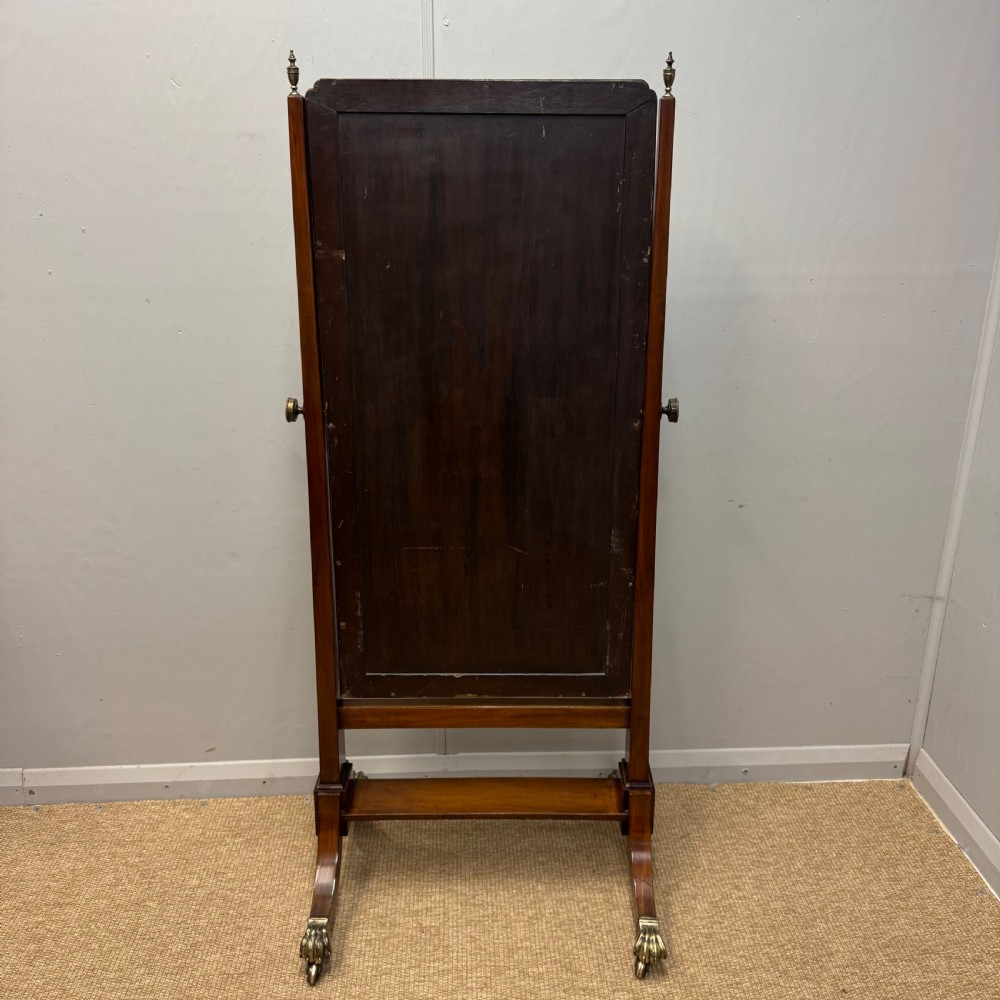 A Regency mahogany cheval mirror featuring a rectangular swivelling mirror frame, turned finials, boxwood inlay, and splayed legs ending in brass castors. View VII