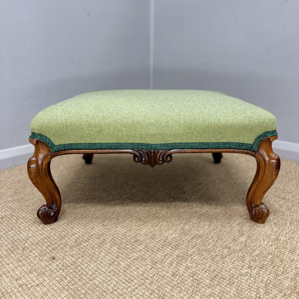 A low Victorian rosewood footstool featuring light green upholstery and hand-carved cabriole legs with scroll feet. View II