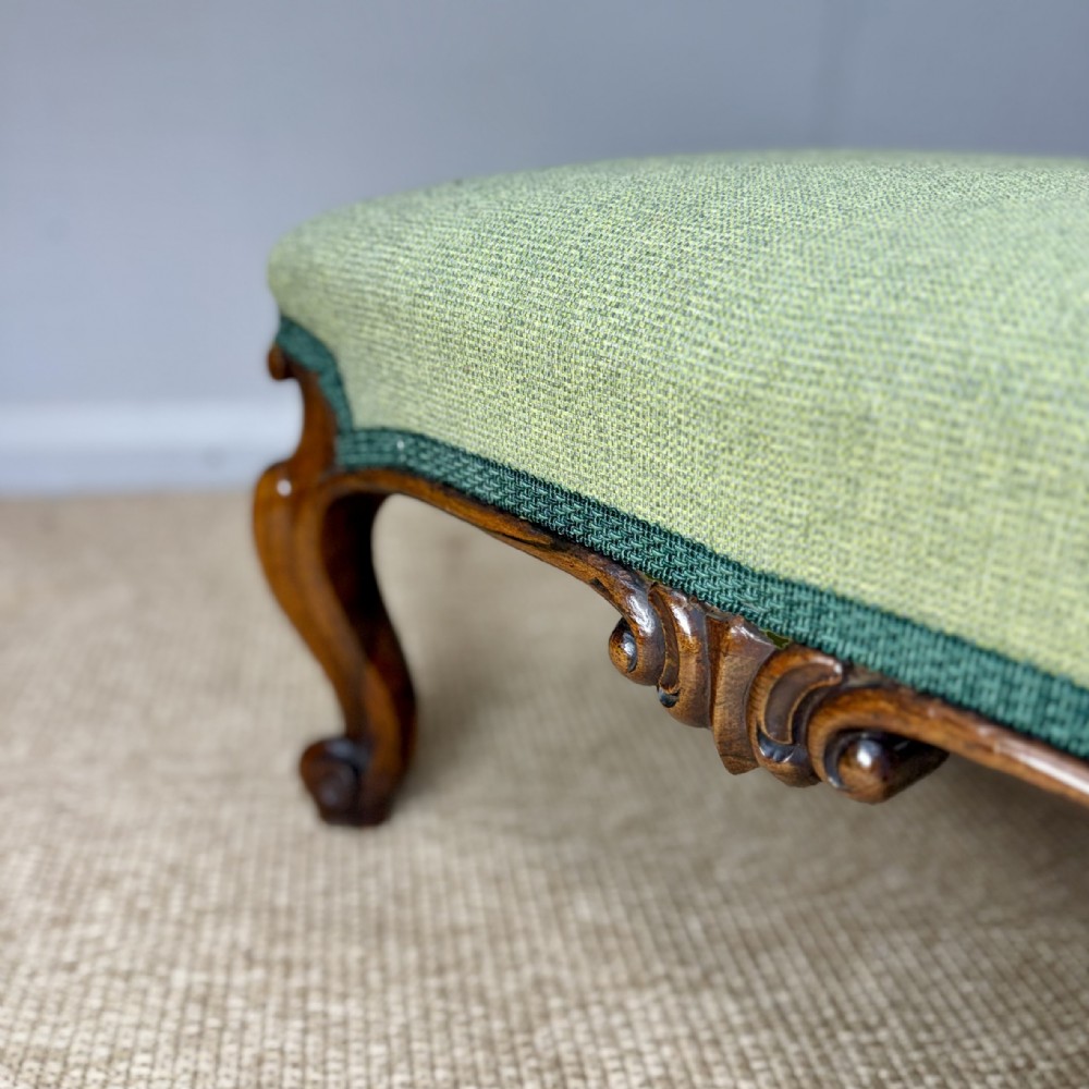 A low Victorian rosewood footstool featuring light green upholstery and hand-carved cabriole legs with scroll feet. View III