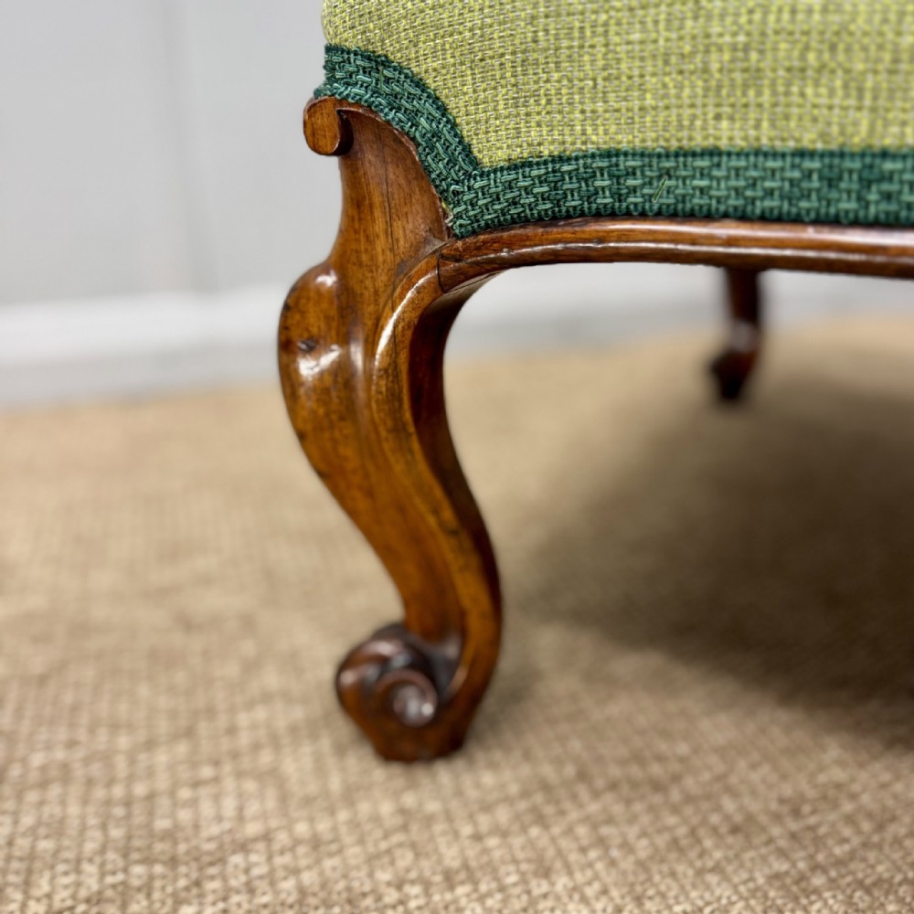 A low Victorian rosewood footstool featuring light green upholstery and hand-carved cabriole legs with scroll feet. View V