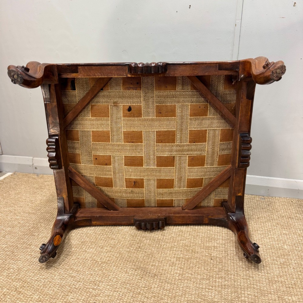 A low Victorian rosewood footstool featuring light green upholstery and hand-carved cabriole legs with scroll feet. View VI