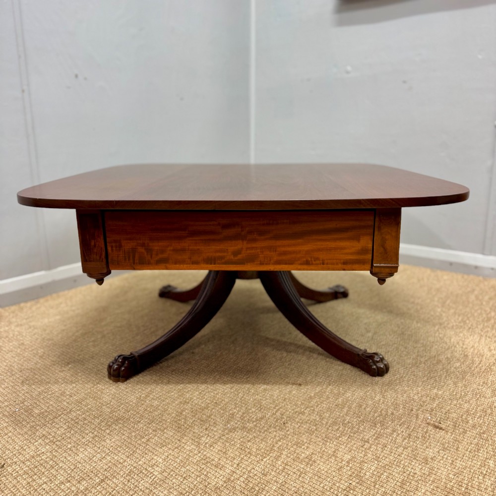 A low English Regency mahogany coffee table with a polished square top, rounded corners, a deep apron, and splayed legs with carved feet. View II