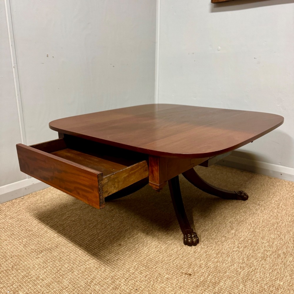 A low English Regency mahogany coffee table with a polished square top, rounded corners, a deep apron, and splayed legs with carved feet. View III