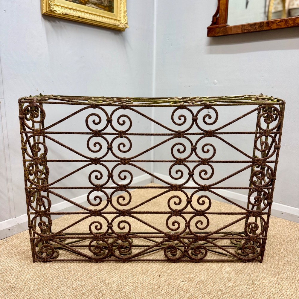 A low rectangular French wrought iron table with ornate C-scroll patterns and a weathered rust finish. View V
