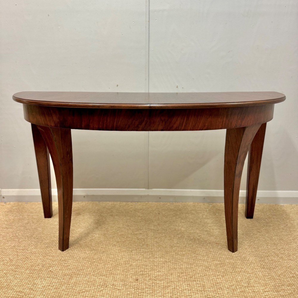 A 19th-century rosewood demilune console table featuring a semi-circular top, plain apron, and four sweeping concave legs.