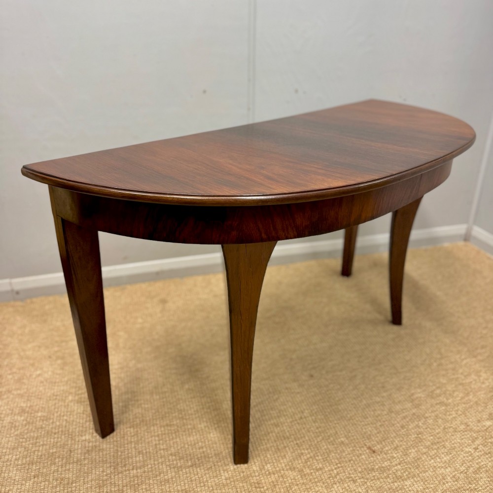 A 19th-century rosewood demilune console table featuring a semi-circular top, plain apron, and four sweeping concave legs. View IV