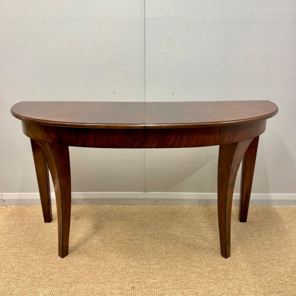 A 19th-century rosewood demilune console table featuring a semi-circular top, plain apron, and four sweeping concave legs. View VII