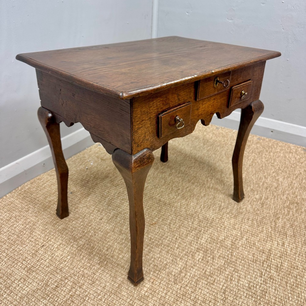 An 18th-century oak low side table featuring cabriole legs, three drawers with brass drop handles, and a shaped apron. View II