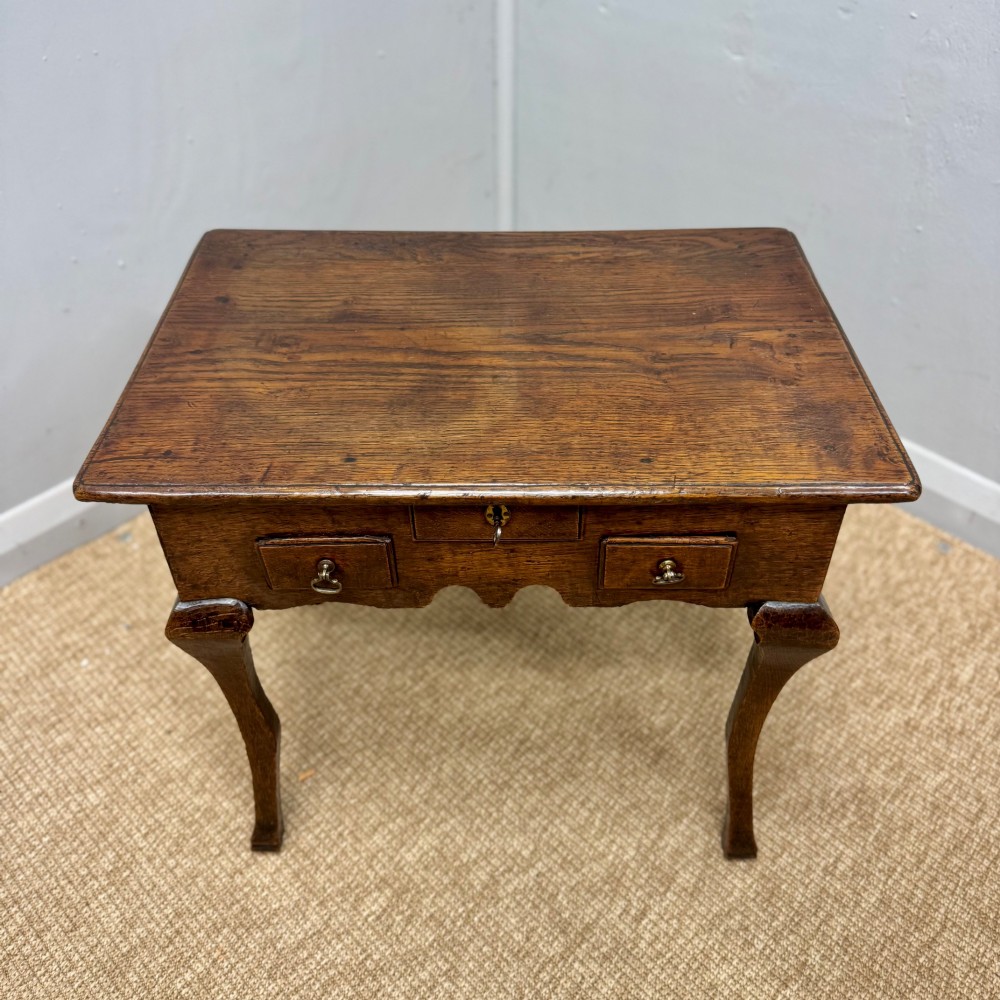 An 18th-century oak low side table featuring cabriole legs, three drawers with brass drop handles, and a shaped apron. View VII