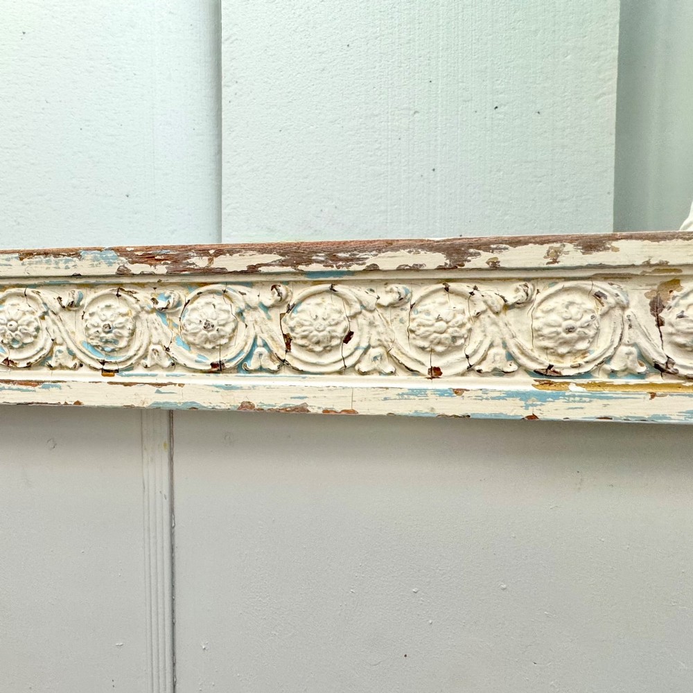 A rectangular 19th-century French overmantel mirror featuring a heavily carved rosette frame with distressed white paint. View IV