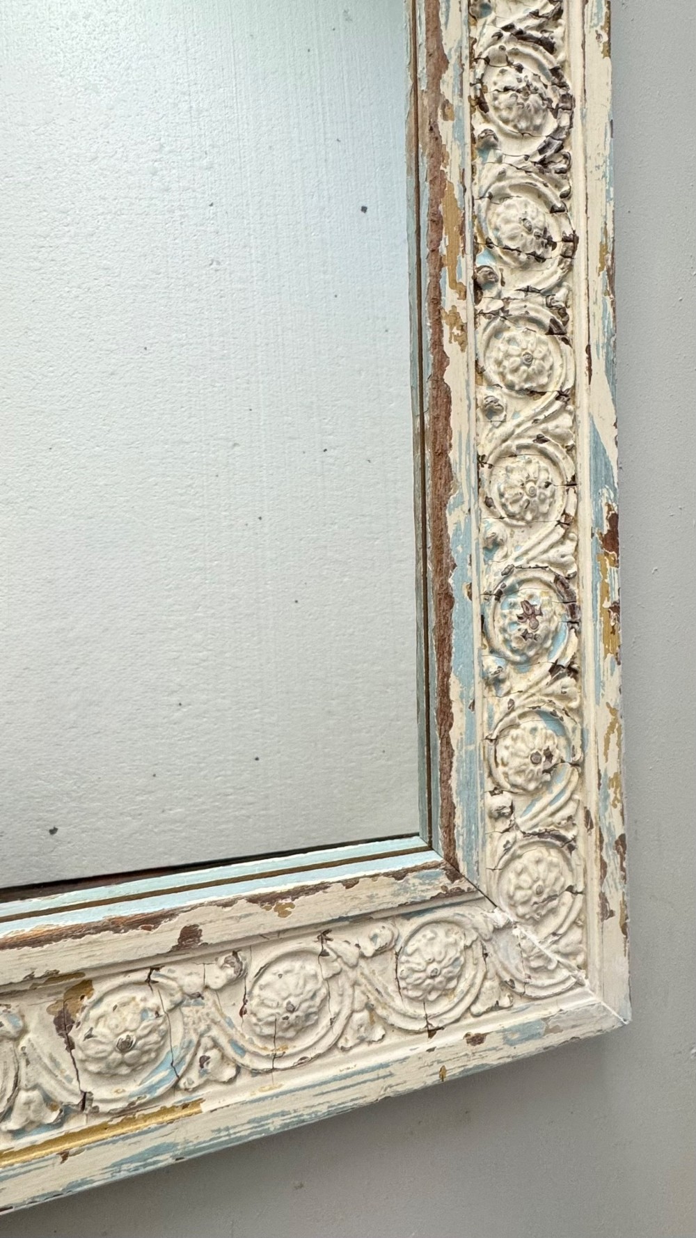 A rectangular 19th-century French overmantel mirror featuring a heavily carved rosette frame with distressed white paint. View VII