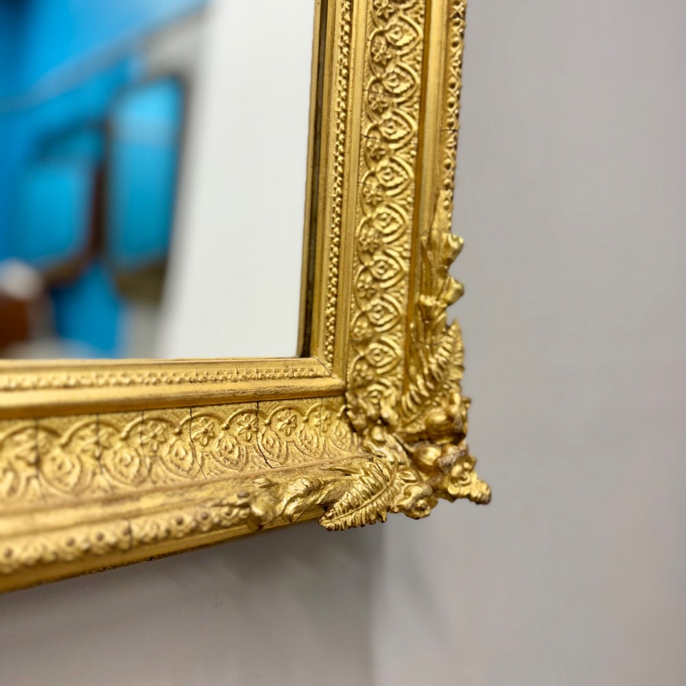A rectangular nineteenth-century English wall mirror featuring a gold gilded frame with carved foliage corner embellishments and beaded moulding. View III