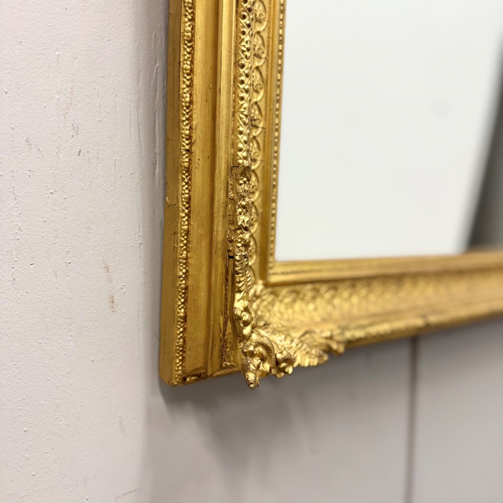 A rectangular nineteenth-century English wall mirror featuring a gold gilded frame with carved foliage corner embellishments and beaded moulding. View IV