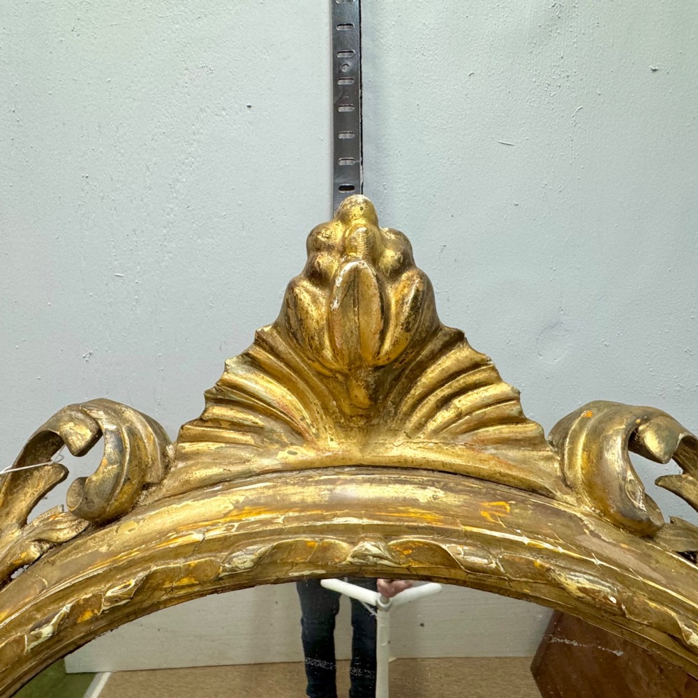 A circular giltwood wall mirror framed in carved acanthus leaves and topped with a shell crest. View VI