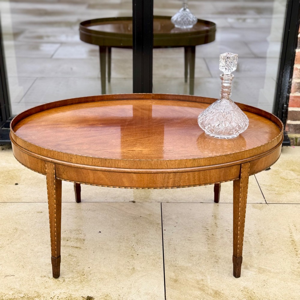 An oval timber coffee table featuring chevron marquetry inlay, a raised rim gallery, and four tapered legs. View II