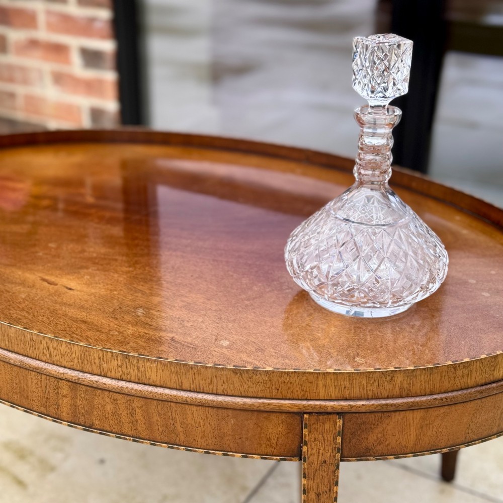 An oval timber coffee table featuring chevron marquetry inlay, a raised rim gallery, and four tapered legs. View III