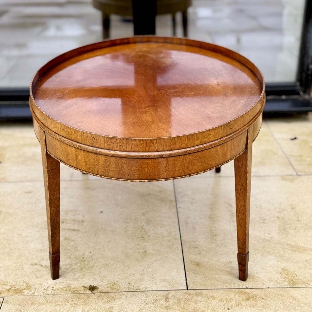 An oval timber coffee table featuring chevron marquetry inlay, a raised rim gallery, and four tapered legs. View VII