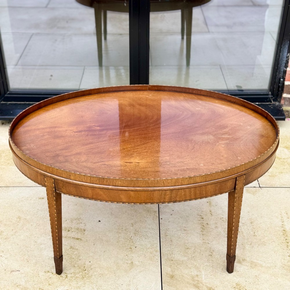 An oval timber coffee table featuring chevron marquetry inlay, a raised rim gallery, and four tapered legs. View VIII