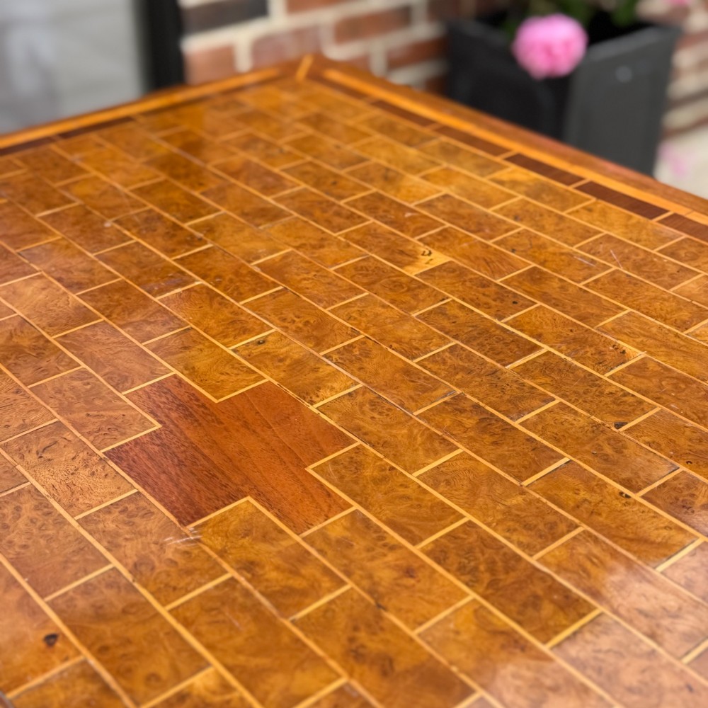 A square antique tilt-top centre table featuring a geometric burr walnut parquetry top framed by an oak border, supported on a faceted pedestal base with castors. View VIII