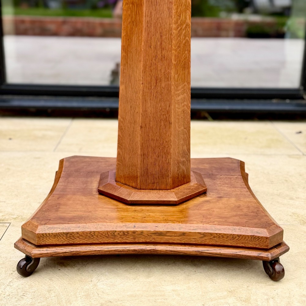 A square antique tilt-top centre table featuring a geometric burr walnut parquetry top framed by an oak border, supported on a faceted pedestal base with castors. View IX