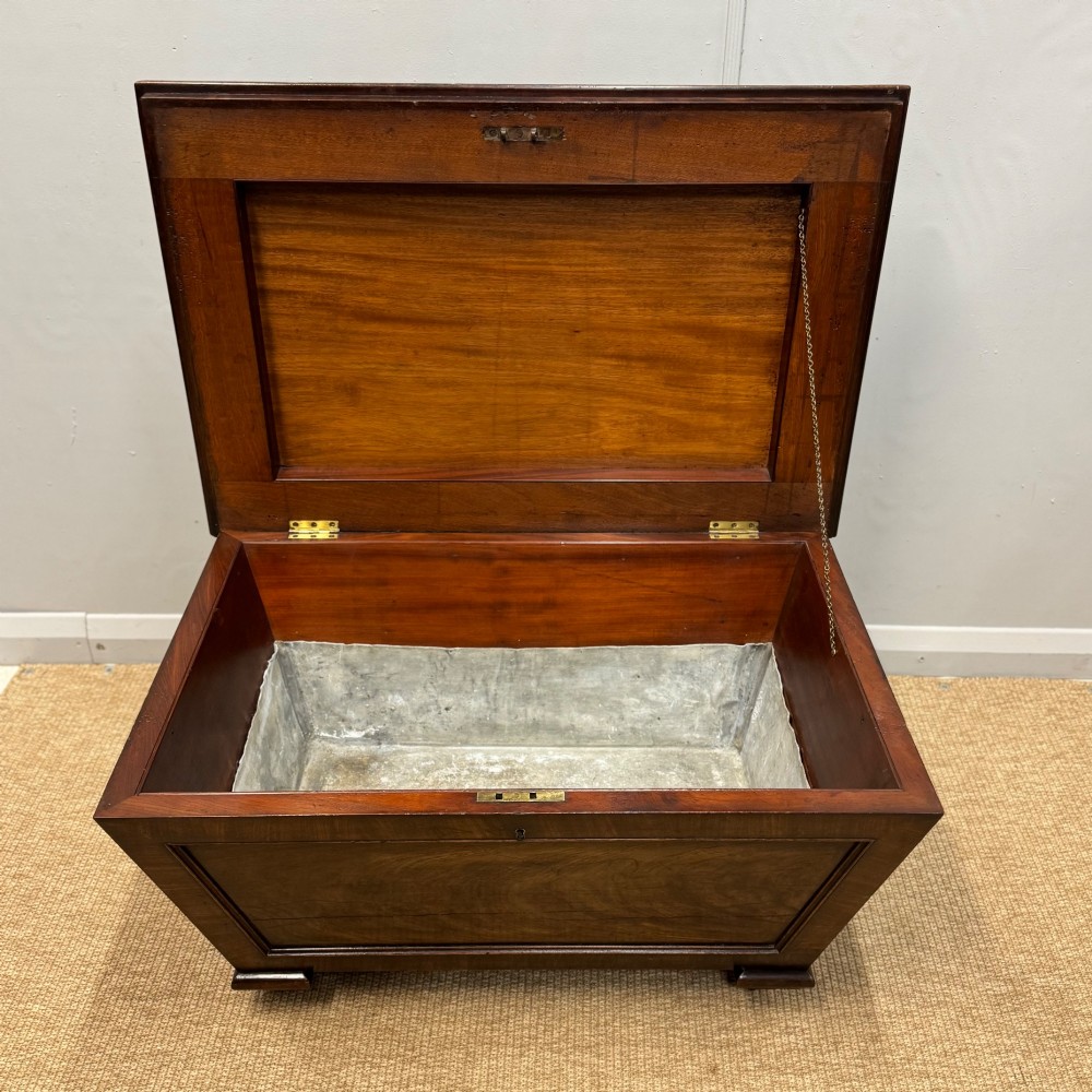 A late Georgian mahogany cellarette displaying a tapered sarcophagus shape with a stepped lid and flame mahogany panels. View VI