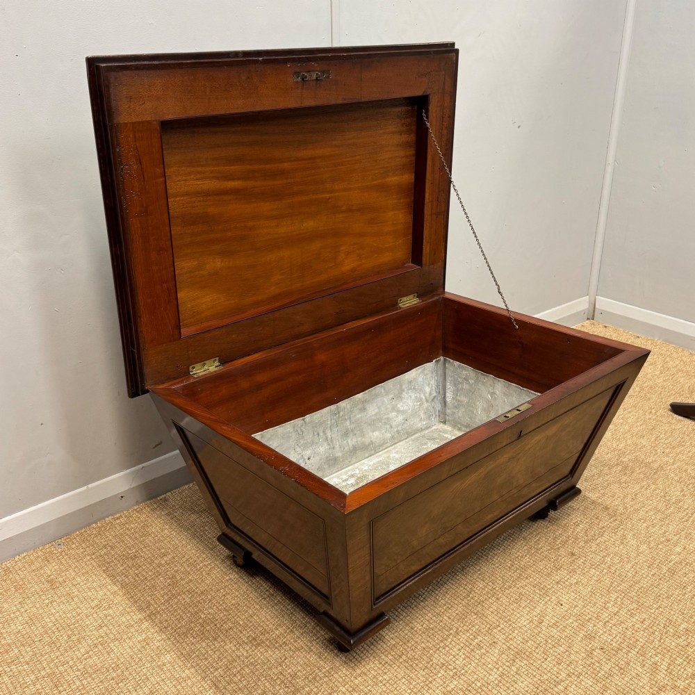 A late Georgian mahogany cellarette displaying a tapered sarcophagus shape with a stepped lid and flame mahogany panels. View VII