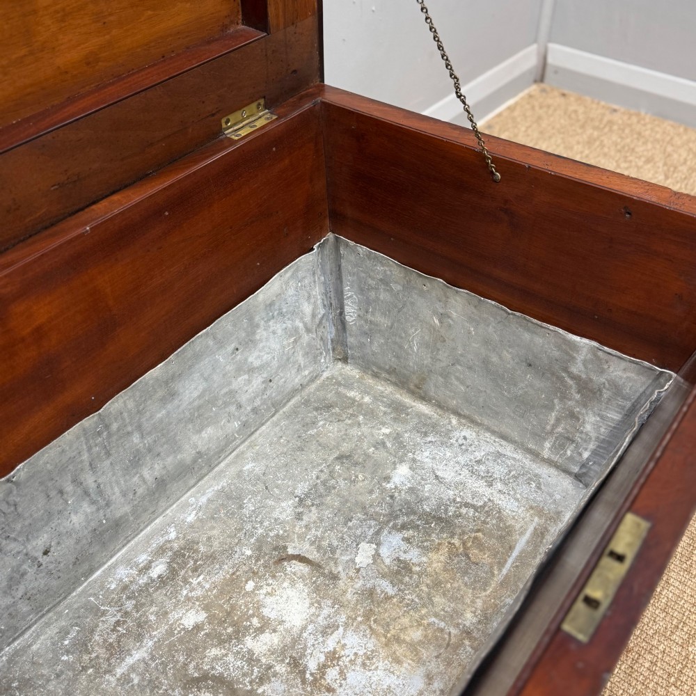 A late Georgian mahogany cellarette displaying a tapered sarcophagus shape with a stepped lid and flame mahogany panels. View VIII