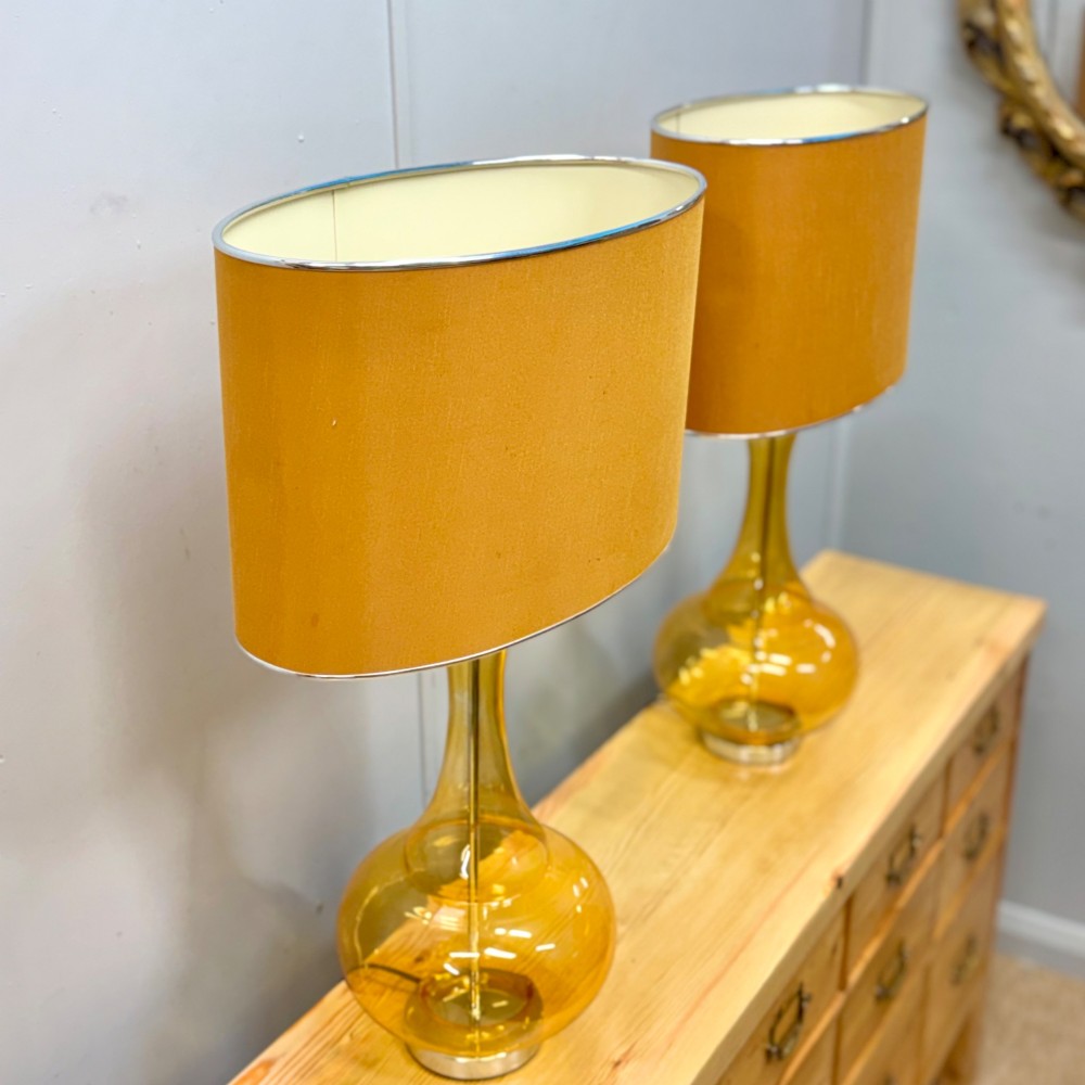 A pair of mid-century amber blown glass table lamps featuring slender necks, bulbous bases, and matching ochre drum shades. View II