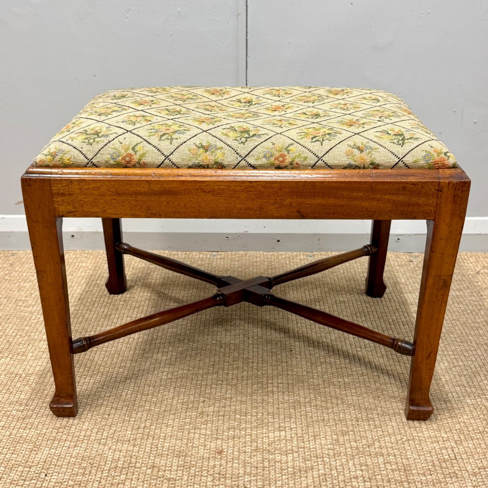 A rectangular mahogany dressing stool with a turned cross stretcher and cream lattice patterned tapestry upholstery. View II