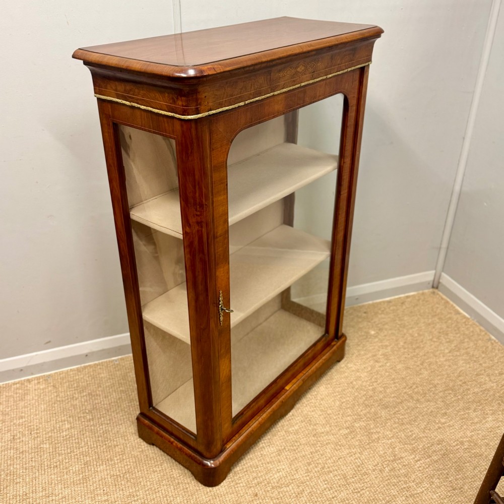 Victorian walnut pier cabinet featuring a single glazed door, floral marquetry inlay on the frieze, brass rim trim, and a three-tier fabric-lined interior. View VII