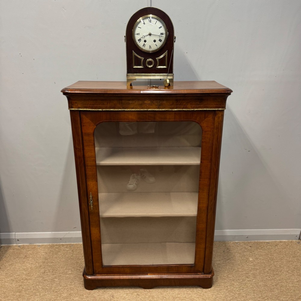 An arched antique French mahogany mantel clock featuring a white face with Roman numerals, decorative brass trim, and a stepped brass base. View XI