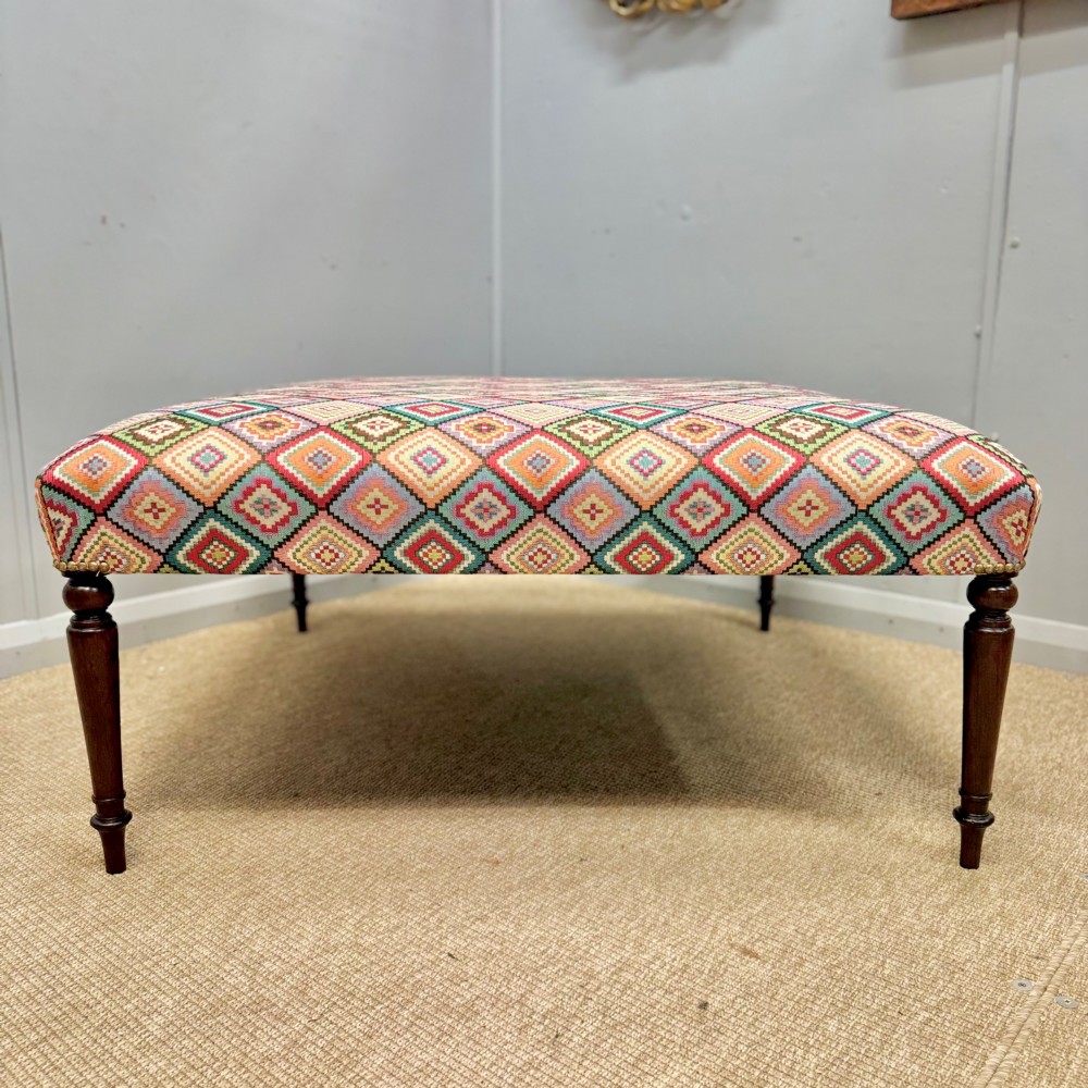 A large rectangular footstool upholstered in a vibrant geometric diamond pattern featuring turned mahogany legs. View VII