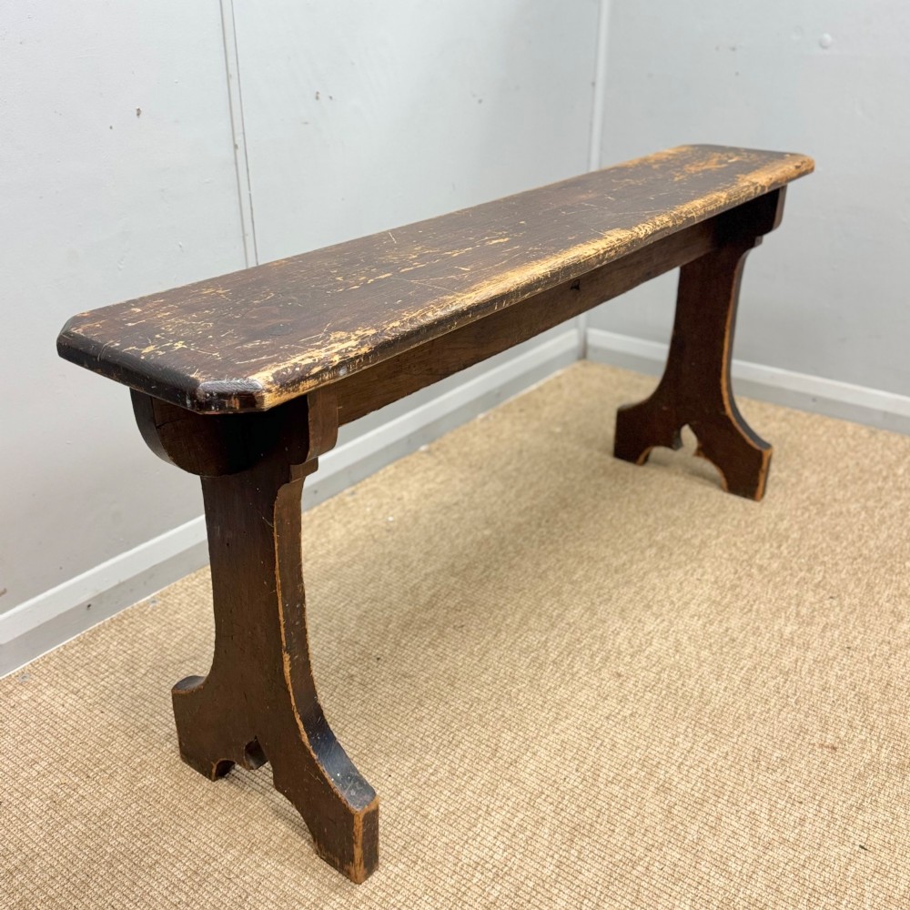 A five-foot antique pine bench featuring a distressed dark brown finish and shaped slab end supports. View II