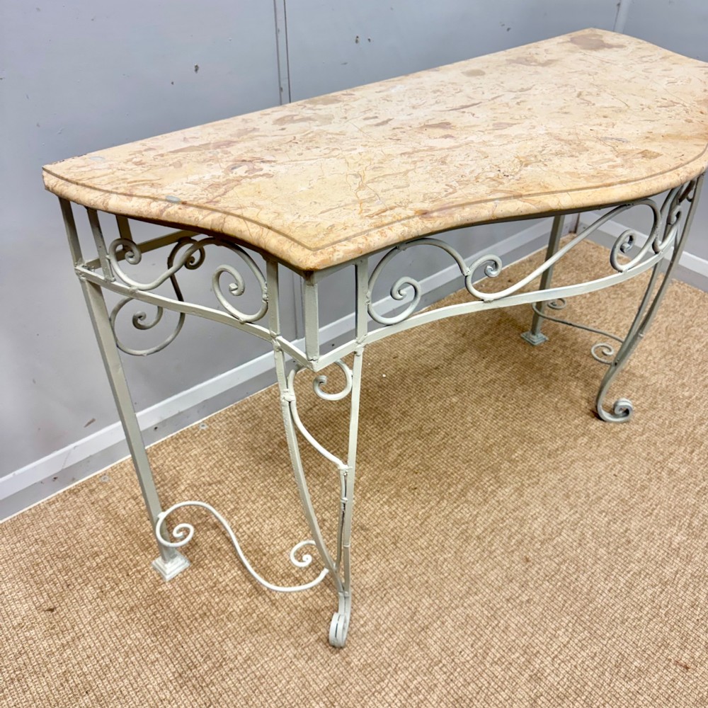 A French wrought iron console table featuring a contoured beige marble top set upon an off-white painted frame with decorative scrollwork. View IV