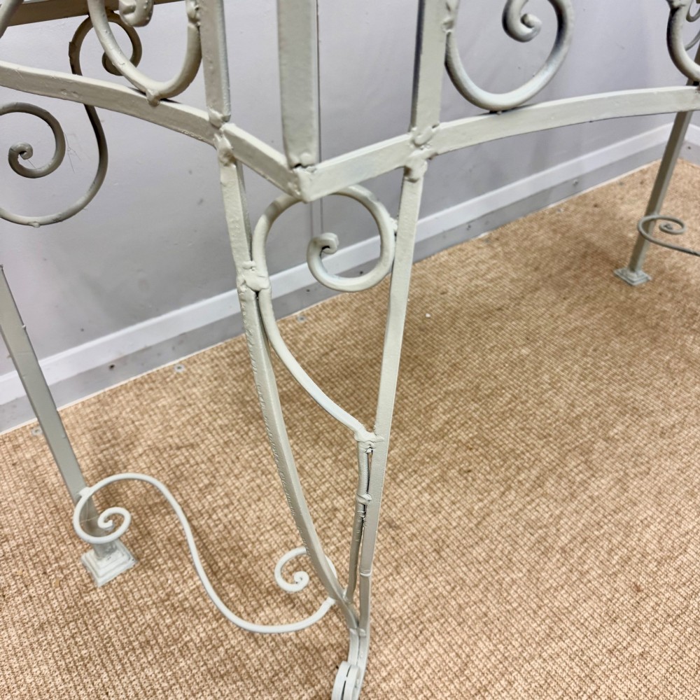 A French wrought iron console table featuring a contoured beige marble top set upon an off-white painted frame with decorative scrollwork. View V