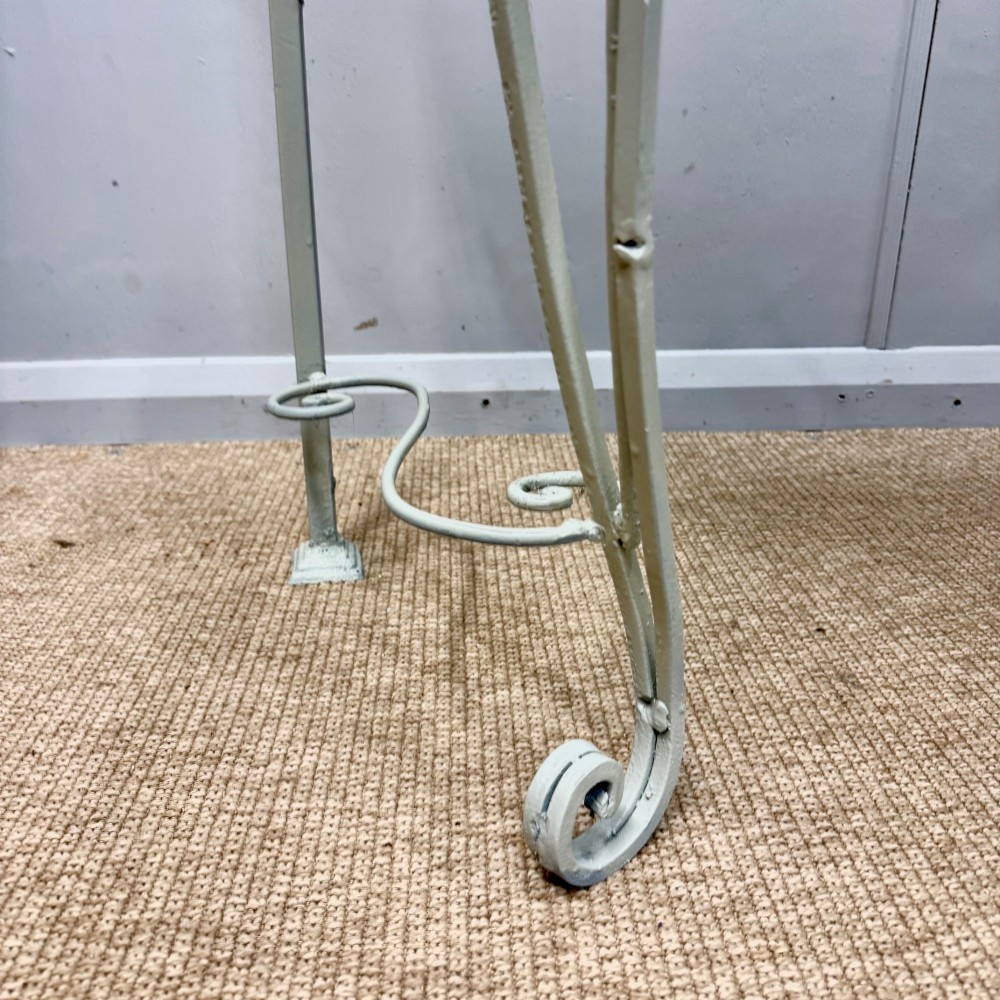 A French wrought iron console table featuring a contoured beige marble top set upon an off-white painted frame with decorative scrollwork. View VI