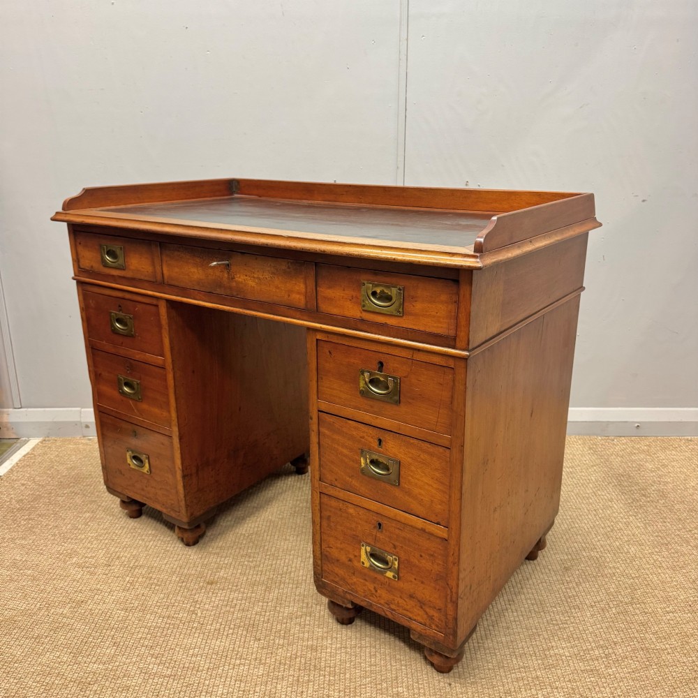 A Victorian military campaign kneehole desk in warm brown wood, featuring an inset leather writing surface, gallery rail, and seven drawers with flush brass handles. View III
