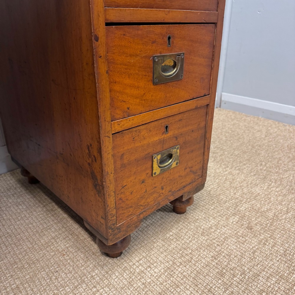 A Victorian military campaign kneehole desk in warm brown wood, featuring an inset leather writing surface, gallery rail, and seven drawers with flush brass handles. View VII