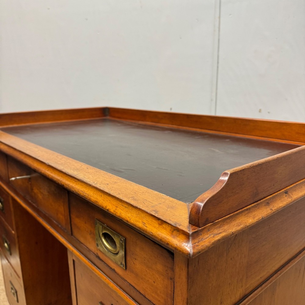 A Victorian military campaign kneehole desk in warm brown wood, featuring an inset leather writing surface, gallery rail, and seven drawers with flush brass handles. View VIII