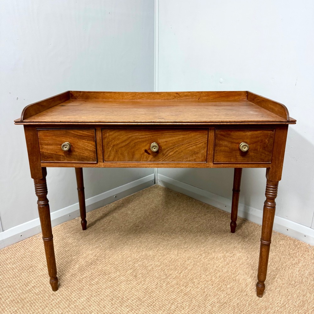 A Regency mahogany dressing table featuring three drawers with round brass knobs, a raised gallery top, and four turned tapered legs. View II