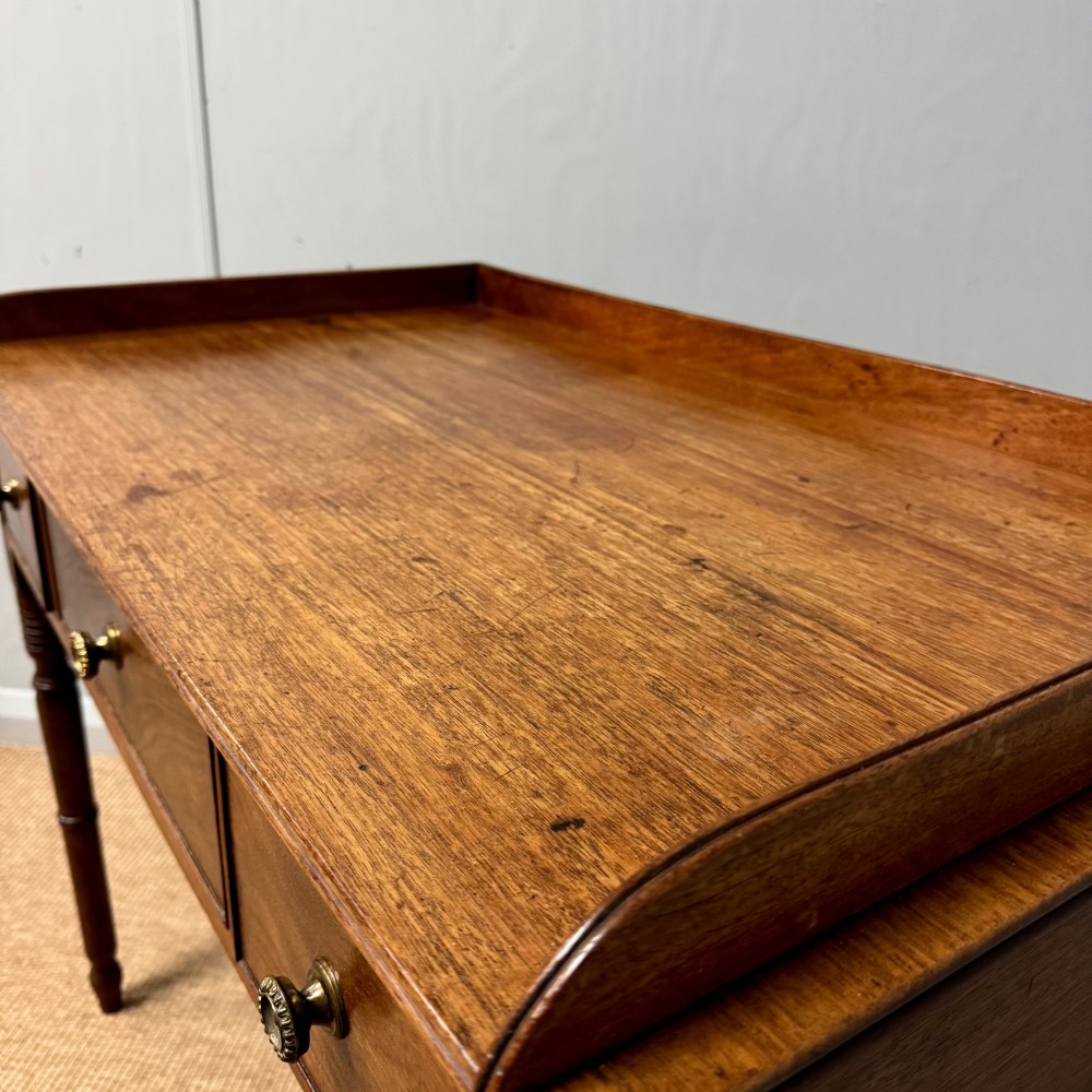 A Regency mahogany dressing table featuring three drawers with round brass knobs, a raised gallery top, and four turned tapered legs. View III