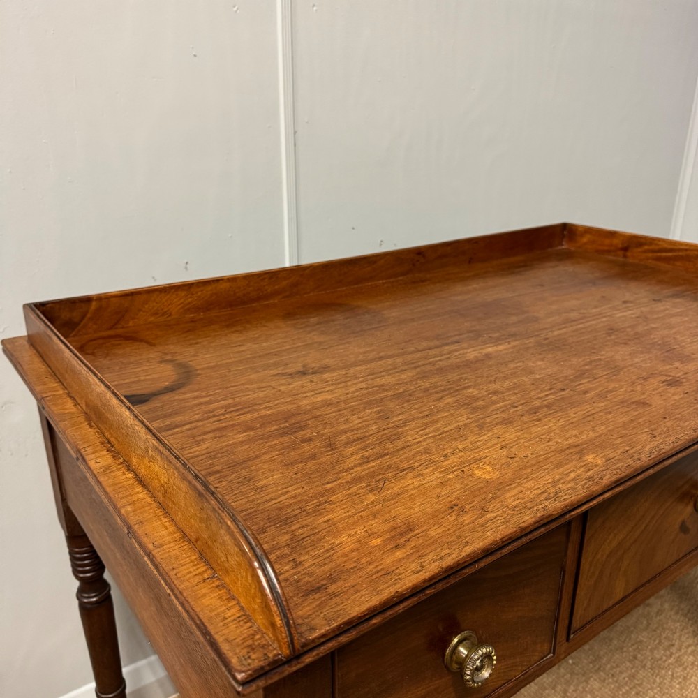 A Regency mahogany dressing table featuring three drawers with round brass knobs, a raised gallery top, and four turned tapered legs. View IV