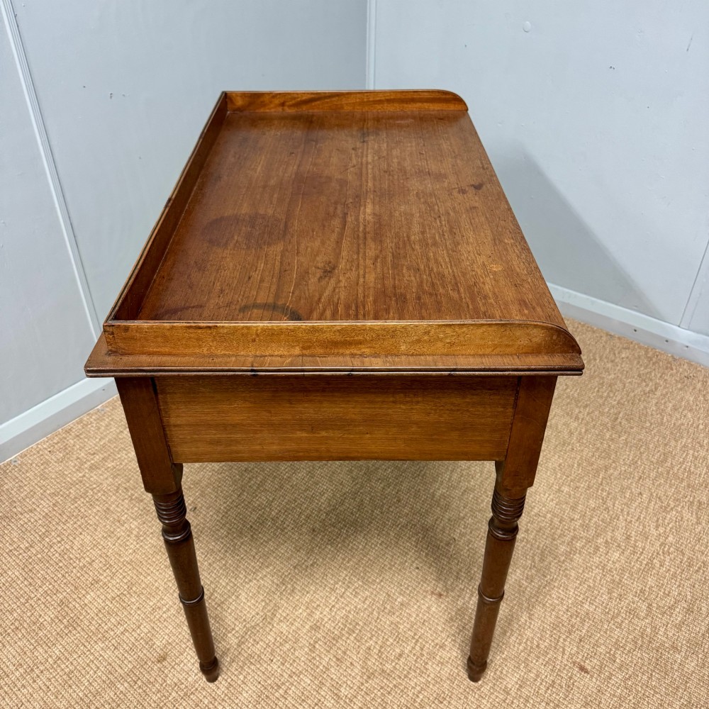A Regency mahogany dressing table featuring three drawers with round brass knobs, a raised gallery top, and four turned tapered legs. View VI